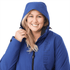 A woman wearing a blue soft shell jacket with a hood, featuring a logo on the front.