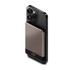 A slim, magnetic wireless power bank in grey is attached to the back of a black smartphone. It features a logo.