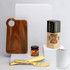 A wooden chopping board, golden cheese knife and server, jar of spread, and coiled twine on a white background with packaging.