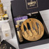 A gourmet gift pack featuring a bamboo cheese board set, assorted snacks, and a selection of condiments in a black box.