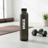 A drink bottle in matte black with a sleek design and white logo, set against a modern backdrop.