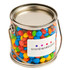 A small silver bucket filled with colourful mini M&Ms in red, blue, green, and yellow, featuring a logo.