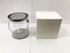 A clear PVC bucket with a silver lid and handle, alongside a plain white box.