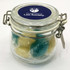 A glass canister with a metal clasp containing twist-wrapped boiled lollies in blue and yellow. It has a logo on the lid.