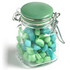 A glass clip lock jar filled with light green and blue humbug sweets, featuring a green lid and a metal clasp.