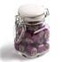 A clip lock jar filled with purple rock candy, showcasing colourful fruit designs within each piece. Glass jar with a metal clasp.