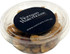 A clear tub filled with assorted nuts, featuring a dark blue circular label with a logo on top.