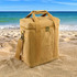 A tan Kraft paper lunch cooler bag with handles and a shoulder strap, placed on sandy beach terrain by the sea.