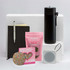 A black drink bottle, notebook, pen, chocolate snakes, a heart-shaped treat, and a portable speaker on a white background.