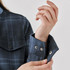 A close-up of a women's plaid jacket featuring a dark blue pattern and visible snap buttons on the cuffs.