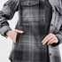 A women's shacket in grey and black Highland plaid with a front pocket and button closure. Features a logo.