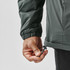 A hand adjusts the drawstring of a dark green thermal jacket, showcasing its elastic cuffs and sleek design.