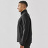 A men's softshell jacket in black, featuring a high collar and a side zip pocket. It has a logo on the chest.