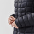 A women's puffer jacket in black, featuring a quilted design and a close-up of the cuff with a logo.