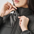 A woman zips up a black puffer jacket with a high collar, showcasing the thermal design.