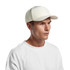 A white perforated cap displayed on a model, featuring a solid front panel and a logo on the side.