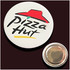A round button badge featuring a logo with a red hat and black text on a white background. It has a metal backing.