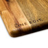 A wooden acacia serving board featuring a smooth finish and the brand logo engraved on one side.