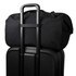 A black duffel bag sits on top of a black suitcase, featuring a trolley handle for easy transport.