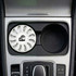 A white air freshener sits in a car cup holder, featuring a circular design and a logo.