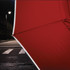A red compact umbrella with a sleek design, partially opened against a night city backdrop and street lighting.
