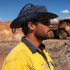 A blue recycled surf hat worn by a man in safety gear, with sunglasses, set against an industrial background.