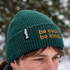 A green ribbed beanie featuring a branding logo and text in orange.