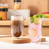 A set of two large double wall glass tumblers, featuring a coffee drink and a pink beverage with lime slices.