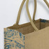 A jute tote bag featuring a natural beige colour with a blue design and sturdy handles. It has branding on the side.