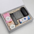 A gift box containing a black drink bottle, snacks, and a card set, all set on shredded paper packaging.