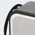 A grey and white portable speaker with a textured surface and a black strap attached.