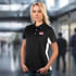 A black and white women's polo shirt featuring a logo, displayed by a model in an indoor setting.