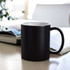 A black ceramic mug with a white interior, placed on a table beside an open magazine.