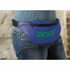 A blue bum bag worn at the waist, featuring a large logo. It has a zippered front pocket and an adjustable strap.
