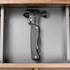 A black survival hammer with multiple tools, displayed in a grey drawer. It features a sleek design and a branding logo.