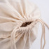 A beige drawstring bag with a gathered opening and matching drawstrings. It has a simple, minimal design.