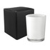 A glass candle in a clear container next to a black box. The candle is white and has a simple design.