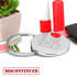 A compact mirror with a shiny silver finish, featuring a logo, placed next to a small plant and makeup items.