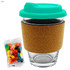 A glass coffee cup with a teal lid, cork band, and a side of colourful jelly beans.