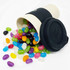 A bamboo cup in cream with a black lid, overflowing with colourful jelly beans in various hues.
