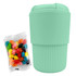 A reusable mint green coffee cup with ribbed texture, accompanied by a pack of colourful jelly beans.