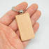 A wooden key ring in a rectangular shape with a silver metal keychain clasp, held in a hand.