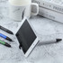 A metal stylus pen in silver, holding a smartphone upright, with blue, green, and black pens nearby.