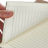 A hand holds a brown Falby notebook with lined, cream-coloured pages. It features a simple design and a logo.