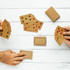 Eco-friendly playing cards in brown recycled material, displayed in hands with a deck and some cards laid out on a wooden surface.