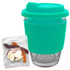 A reusable coffee cup with a turquoise silicone sleeve and a transparent glass body, accompanied by a pack of jelly candies.