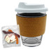 A glass coffee cup with a cork band and a white lid, alongside a bag of mixed lollies in various colours.