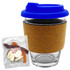 A glass coffee cup with a cork band and blue lid, accompanied by a bag of mixed lollies in various colours.