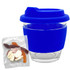A blue glass coffee cup with a silicone lid and sleeve, alongside a packet of mixed lollies in various colours.