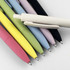 A collection of plastic pens in various colours, including pink, yellow, green, blue, lilac, black, and white, with a logo.